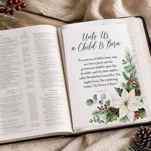Può includere: Una Bibbia aperta con una pagina bianca inserita che riporta il testo Unto Us a Child Is Born e il versetto di Isaia 9:6. La pagina è decorata con un'illustrazione ad acquerello di una stella di Natale bianca, rami di pino e bacche rosse.