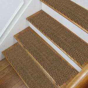 以下が含まれることがあります： 茶色の織り込まれたテクスチャパターンが施された階段の踏み板。踏み板は、白いライザーと木製のトリムが付いた木製の階段に取り付けられています。このデザインは、階段に装飾的で機能的な要素を追加します。