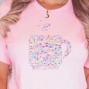 May include: Pink t-shirt with a coffee cup design made up of the word "coffee" in various colors.