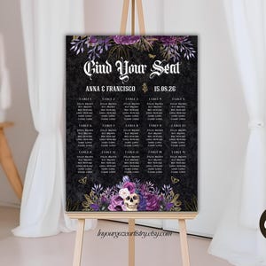 May include: A black wedding seating plan displayed on an easel, decorated with floral and skull motifs. The sign says "Find Your Seat" and lists names under table numbers. Purple and gold floral designs frame the top and bottom. The date is 15.08.26.
