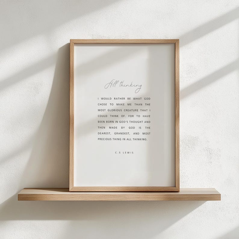 May include: A framed print with the text "All thinking" and a quote by C.S. Lewis. The quote is in black font on a white background, framed by a light brown wooden frame. The print is displayed on a light brown wooden shelf.