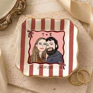 May include: A square ceramic trinket dish with scalloped edges, featuring a red and white vertical striped pattern. The center displays a custom illustration of two people with the letters T and R, a small heart, and the date Jan 24, 2026.
