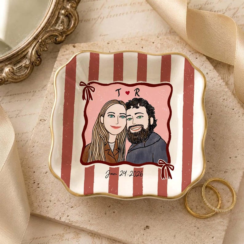 May include: A square ceramic trinket dish with scalloped edges, featuring a red and white vertical striped pattern. The center displays a custom illustration of two people with the letters T and R, a small heart, and the date Jan 24, 2026.