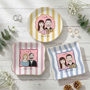 Pu&ograve; includere: Tre piattini in ceramica con illustrazioni personalizzate di coppie. Un piattino rotondo a righe gialle e due piattini quadrati a righe rosa o blu. Ogni piattino mostra una coppia, le iniziali T e R con un cuore e July 24, 2026.