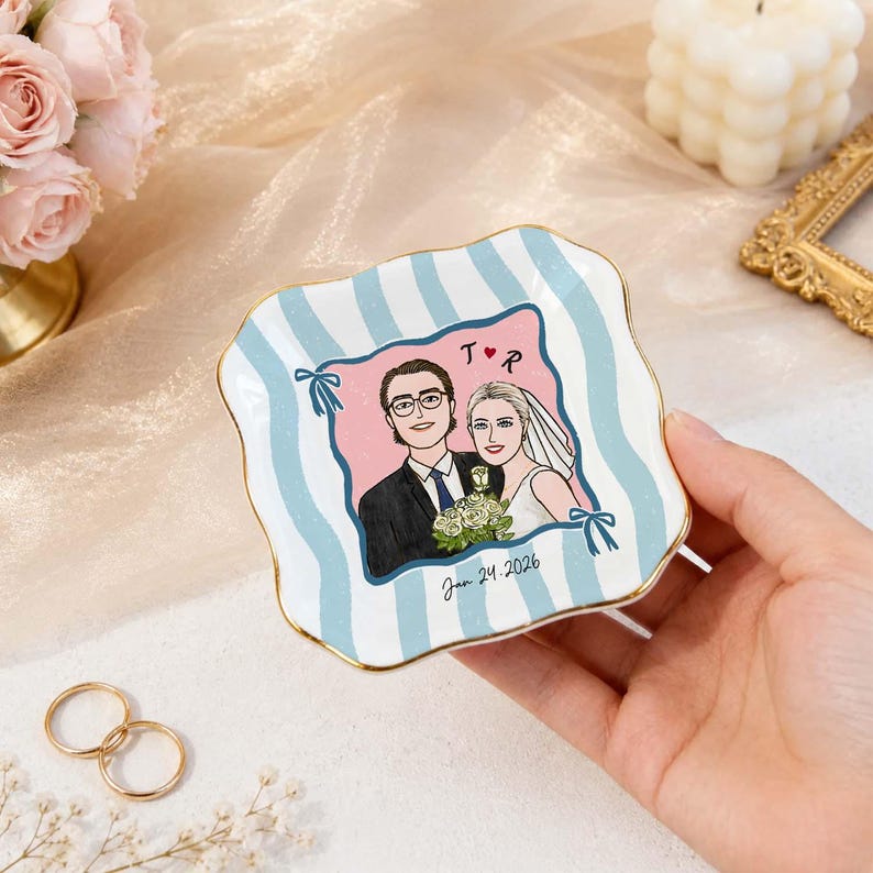 May include: A square ceramic trinket dish with wavy edges and a gold-painted rim. The dish features a light blue and white striped pattern and a central illustration of a couple with the text T heart R and the date Jan 24, 2026.