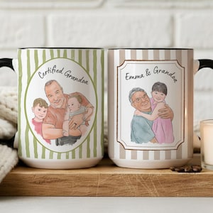 May include: Two ceramic mugs with black handles. The left mug has green vertical stripes and a circular illustration of a man with two children and the text Certified Grandpa. The right mug has beige stripes, a rectangular frame, an illustration of a man and a child, and the text Emma & Grandpa.