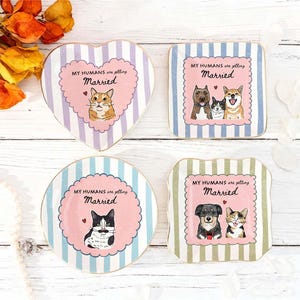 May include: Four ceramic trinket dishes with striped backgrounds and scalloped pink centers. Each dish features illustrations of cats or dogs and the text "MY HUMANS are getting Married." The shapes include a heart, a square, a circle, and a square.