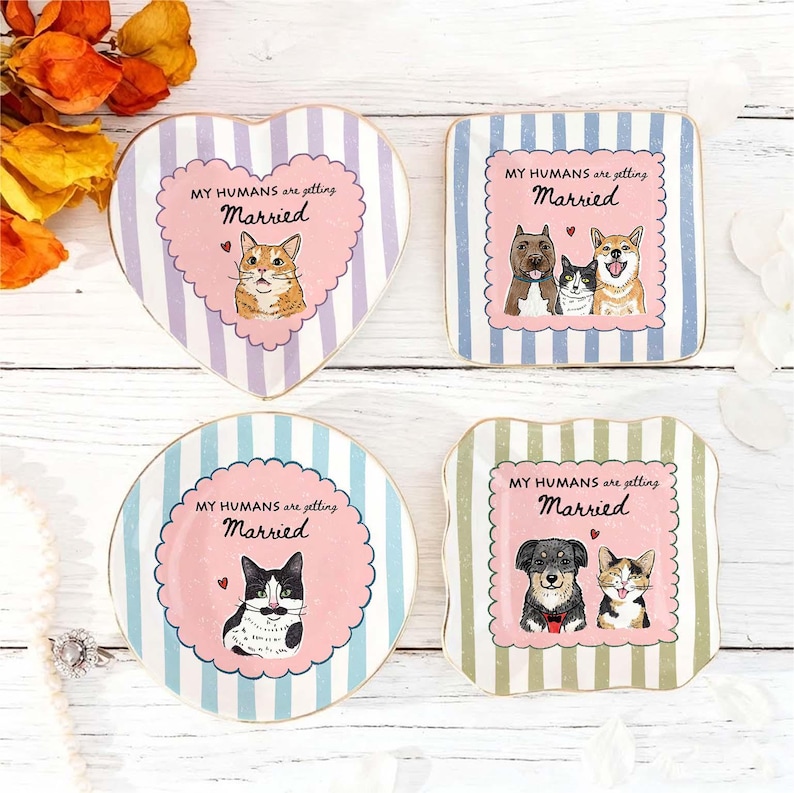 May include: Four ceramic trinket dishes with striped backgrounds and scalloped pink centers. Each dish features illustrations of cats or dogs and the text "MY HUMANS are getting Married." The shapes include a heart, a square, a circle, and a square.