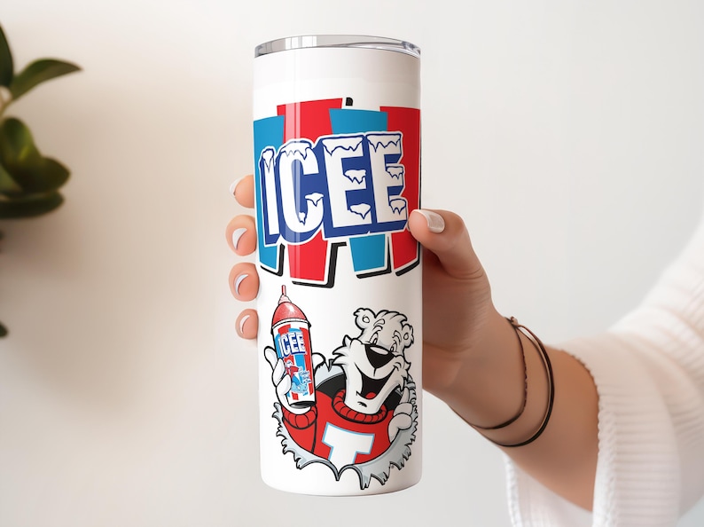 Op de afbeelding: Witte ge&iuml;soleerde tumbler met het woord "ICEE" in blauw en rood. Een cartoonbeer in een rode trui houdt een ICEE-drank vast. De tumbler is cilindrisch en heeft een zilveren deksel.