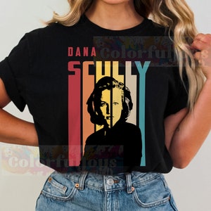 May include: Black t-shirt with a retro-style graphic of Dana Scully from the X-Files. The graphic features a silhouette of Scully with a rainbow stripe background and the text "Dana Scully".