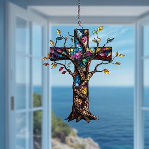 Op de afbeelding: Een hangend ornament in de vorm van een kruis, met een bruine boomstam en takken die om een centrum van glas-in-lood zijn gewikkeld. Het glas toont een mozaïek van levendige kleuren zoals blauw, rood, geel en paars, met kleine gekleurde blaadjes.