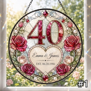 May include: A circular stained glass suncatcher featuring the number 40 in red glass, surrounded by red and pink roses and white pearls. A central heart contains the text Emma & James and EST. 06.20.1986. The piece hangs from a black metal chain.