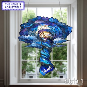 May include: A stained glass suncatcher featuring a swirling tornado design in shades of deep blue, light blue, and white, with a golden centre. The piece includes a hanging chain and the name Jonh in white script. Text reads THE NAME IS ADJUSTABLE.