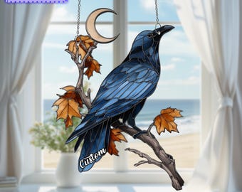 May include: A stained glass suncatcher featuring a dark blue raven perched on a brown branch with orange autumn leaves and a crescent moon. The piece includes a metal chain for hanging and text that reads THE NAME IS ADJUSTABLE and Custom.