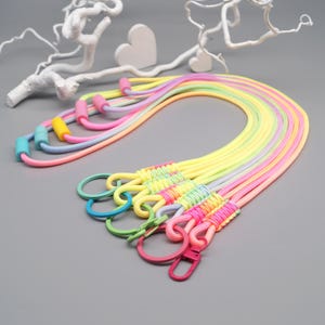 Könnte beinhalten: Ein Set aus fünf Schlüsselbändern aus neonfarbenem Nylonschnur in Gelb, Pink, Grün und Blau. Jedes Schlüsselband verfügt über einen passenden Kunststoffring und einen Karabinerverschluss sowie verstellbare Schiebeperlen in Kontrastfarben.