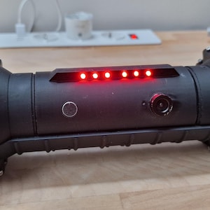 Könnte beinhalten: Ein schwarzer Roboter mit zwei großen Rädern an jedem Ende. Der Roboter hat eine Reihe roter Lichter oben.