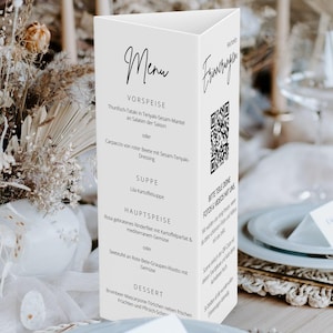 May include: A white, triangular menu card with black script, featuring sections for starters, soup, main course, and dessert. A QR code is printed on the side. The menu is set on a table with floral arrangements.