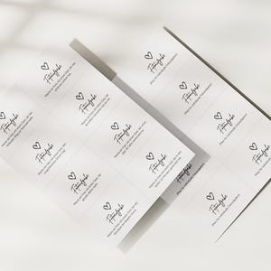 May include: Two white rectangular sheets featuring a grid of small cards with black text and a heart icon. Each card displays the German word Fotoaufgabe followed by specific instructions for guests to take photos, with some cards left blank for custom tasks.