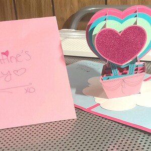 Tarjeta emergente con globo aerostático en forma de corazón para el día de San Valentín.