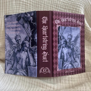 May include: A hardcover book titled The Heartstring Duet by Liv Zander with a dark maroon spine and a purple-toned cover featuring a gothic illustration of a person and a skeleton. The back cover includes the text: You can't have love without embracing grief. Pain is the price we pay for participating in life.