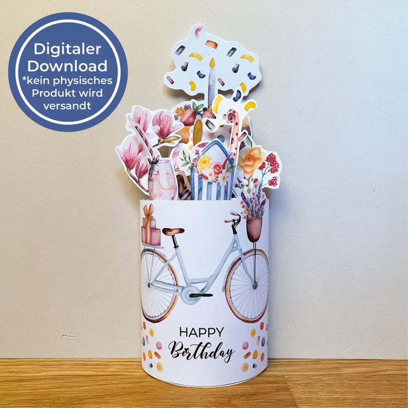Peut inclure: Carte pop-up blanche avec un motif aquarelle. La carte repr&eacute;sente un v&eacute;lo avec un panier de cadeaux et les mots "Happy Birthday". Le haut de la carte pr&eacute;sente un arrangement floral et une forme d'arbre. Un cercle bleu avec du texte est dans le coin sup&eacute;rieur gauche.
