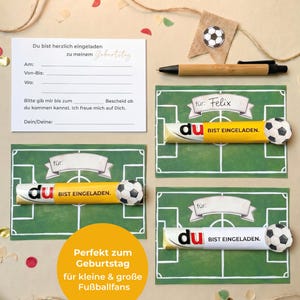 May include: A set of soccer-themed birthday party invitations and decorations. The invitations are designed to look like a soccer field, with a chocolate bar that says "BIST EINGELADEN" and a soccer ball. Includes a pen and a banner.