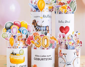 Può includere: Cinque biglietti d'auguri cilindrici con colorate illustrazioni ad acquerello. I disegni includono un bassotto, un cocktail, una bicicletta e composizioni floreali. Il testo include Happy Birthday, Vielen Dank, Alles Liebe zum GEBURTSTAG e AUF DICH.