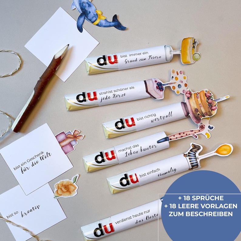 Peut inclure: Plusieurs barres chocolat&eacute;es d&eacute;cor&eacute;es avec du texte allemand, avec des phrases comme &laquo; Tu es un cadeau pour le monde &raquo; et &laquo; Tu m&eacute;rites le meilleur aujourd'hui &raquo;. Des d&eacute;coupes d&eacute;coratives incluent une baleine, un crayon et des bo&icirc;tes cadeaux.