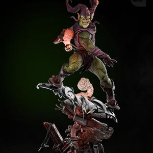 May include: Green Goblin action figure with a green and purple costume, holding a pumpkin bomb. The figure is posed in mid-air, flying on a glider. The figure is standing on a base with a destroyed building.