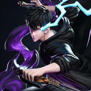 May include: A detailed figurine of a character with black hair and a black hooded jacket, holding two swords. The figure is surrounded by purple and blue energy effects, with blue lightning-like accents near the eyes. The figurine has a dynamic pose.
