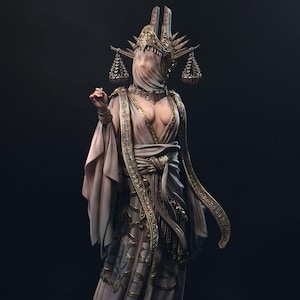 May include: A detailed sculpture of a robed figure with a veiled face, adorned with ornate gold accents. The figure wears a headdress with hanging scales and intricate gold trim on the robe. The color palette is muted with a focus on gold and beige tones.