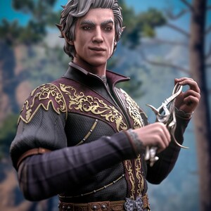 Puede incluir: Un hombre con orejas puntiagudas y cabello plateado lleva una túnica oscura y adornada con bordados dorados. Sostiene una daga de plata con un mango decorativo.