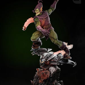 May include: Green Goblin action figure with a green and purple costume, holding a pumpkin bomb. The figure is posed in a dynamic action pose, standing on a black and gray base with a red and orange lava-like effect.