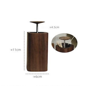 May include: A dark brown wooden toothpick holder, approximately 11cm tall, 6cm wide, and 4.5cm in diameter at the top. The holder has a cylindrical shape with a lid and a small, round handle. The image also shows a close-up of the inside of the holder.