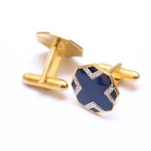 Puede incluir: Un par de gemelos de oro con esmalte azul y detalles de diamantes. Los gemelos tienen un diseño geométrico.