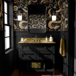 Può includere: Un mobile da bagno nero con piano d'appoggio dorato, rubinetteria nera e specchio rettangolare. Le pareti sono decorate con una carta da parati a motivi di serpenti neri e oro. Due applique affiancano lo specchio e un asciugamano giallo è appeso di lato.