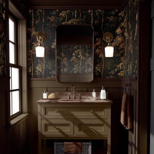 Puede incluir: Un baño con un tocador marrón oscuro, un espejo rectangular y un papel pintado con un tema forestal. El tocador tiene dos cajones y una encimera con un grifo y varios artículos de tocador. Dos apliques con pantallas blancas flanquean el espejo.