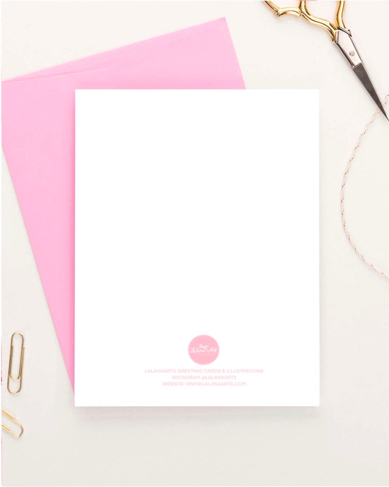 May include: A blank white greeting card with a pink envelope. The back of the card has a pink circle with a logo and the text "LAANAMARTS GREETING CARDS & ILLUSTRATIONS INSTAGRAM @LAANAMARTS WEBSITE: WWW.LAANAMARTS.COM"