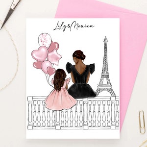 May include: A greeting card with a black and white illustration of two people standing on a balcony overlooking the Eiffel Tower. The people are holding pink balloons and the card says "Lily & Monica".