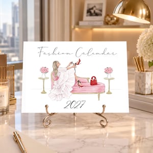 Pode incluir: Um calendário de moda 2027 com a ilustração de uma pessoa de vestido branco sentada numa chaise longue cor-de-rosa, a calçar saltos altos vermelhos. A cena inclui duas mesas de apoio com ramos de flores cor-de-rosa e uma mala vermelha.