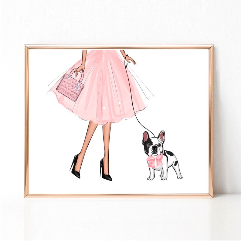 Op de afbeelding: Een vrouw in een roze tule rok en zwarte hakken loopt met een zwart-witte Franse bulldog met een roze strik. Ze draagt een roze handtas.