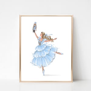 Puede incluir: Una bailarina en un tutú azul y dorado sostiene un cascanueces en su mano derecha. Está bailando de puntillas con la pierna izquierda extendida. El fondo es blanco.