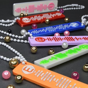 May include: Six colourful keychains with a white chain and a Spotify logo. Each keychain has a different colour and a unique sound wave pattern.