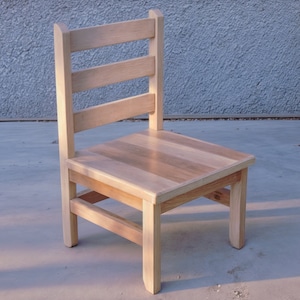 May include: A simple wooden chair with a light wood finish. The chair has a slatted back and a solid seat.