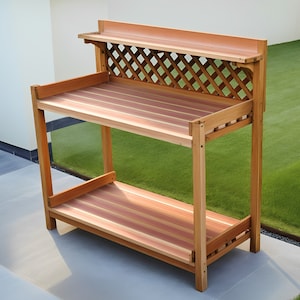 May include: A wooden garden work table with two shelves. The top shelf has a lattice design and the bottom shelf is solid. The table is made of natural wood with a reddish-brown colour.
