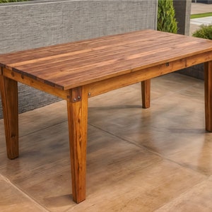 May include: A rustic wooden dining table with a natural brown finish. The table has a rectangular top and four sturdy legs. The table is made of reclaimed wood and has a distressed look.