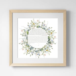 May include: A framed print featuring a floral wreath design surrounding text. The wreath includes green leaves, and small flowers in shades of pink, yellow, and blue. The frame is a light wood color, and the print is on white paper.