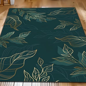 May include: A rectangular rug featuring a dark teal backdrop adorned with a gold leaf pattern. The leaves are stylized and spread across the rug. The rug is positioned on a wooden floor.