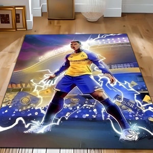 Könnte beinhalten: Ein bunter Teppich mit einer Cartoon-Illustration eines Fußballspielers in einem gelben und blauen Trikot, der auf einem Feld mit einem Stadion im Hintergrund steht. Der Spieler ist von Blitzen umgeben und der Text "NASSR FC" ist im Hintergrund sichtbar.