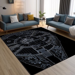 May include: A black and white area rug with a detailed outline of the Millennium Falcon spaceship. The rug is laid out on a hardwood floor in a living room setting.